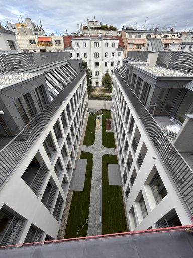 Blick auf einen Innenhof mit modernen Gebäuden und Grünflächen zwischen den Häusern.