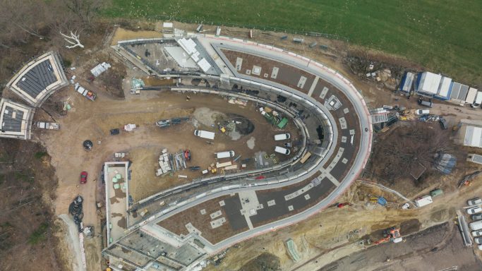 Baugrube mit Kurven und verschiedenen Baustellenfahrzeugen im ländlichen Gebiet.